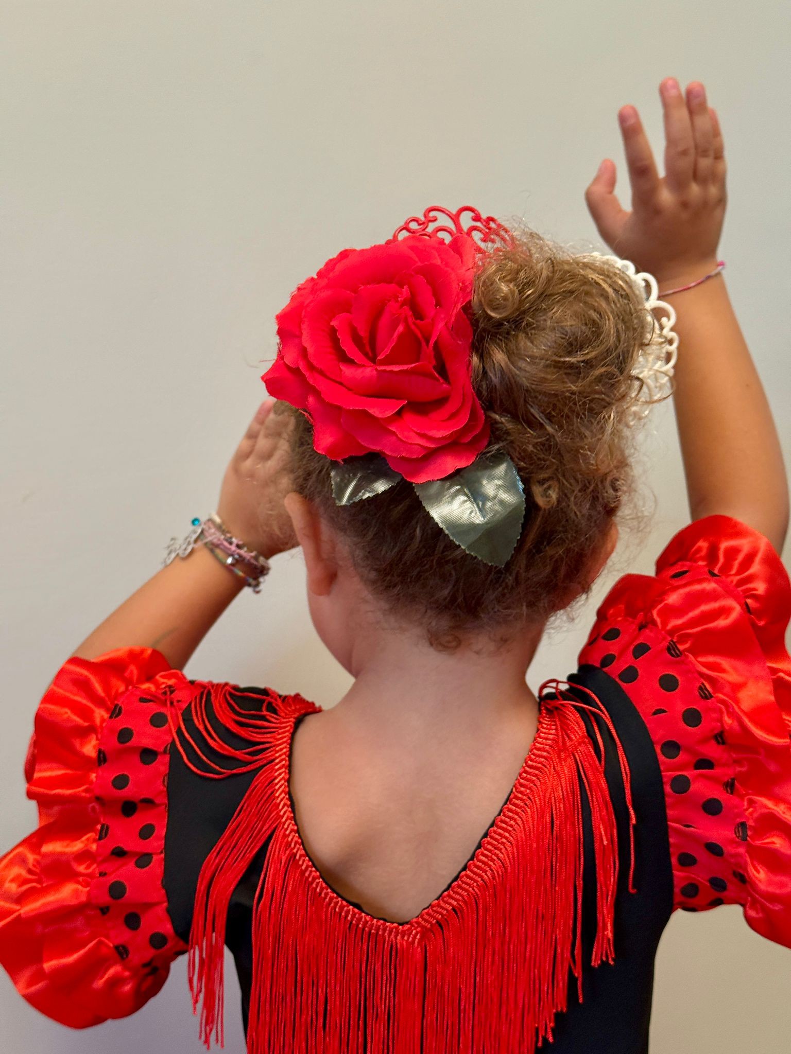 Bambina di spalle con abito rosso e nero durante una lezione di flamenco per bambini a Roma